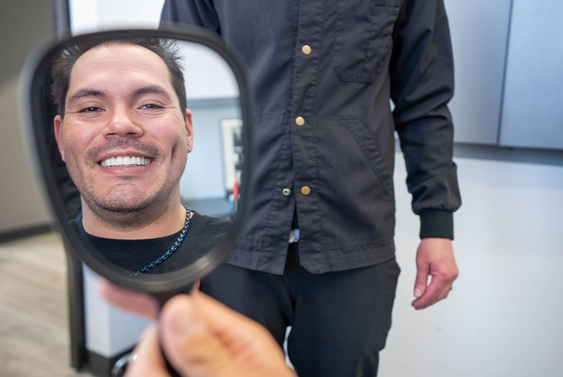 Patient smiling into mirror after dental implant