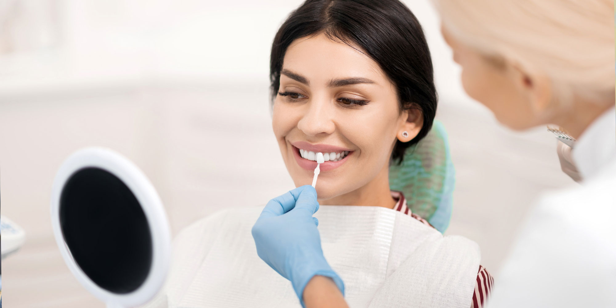 Doctor holding up veneers to patients mouth