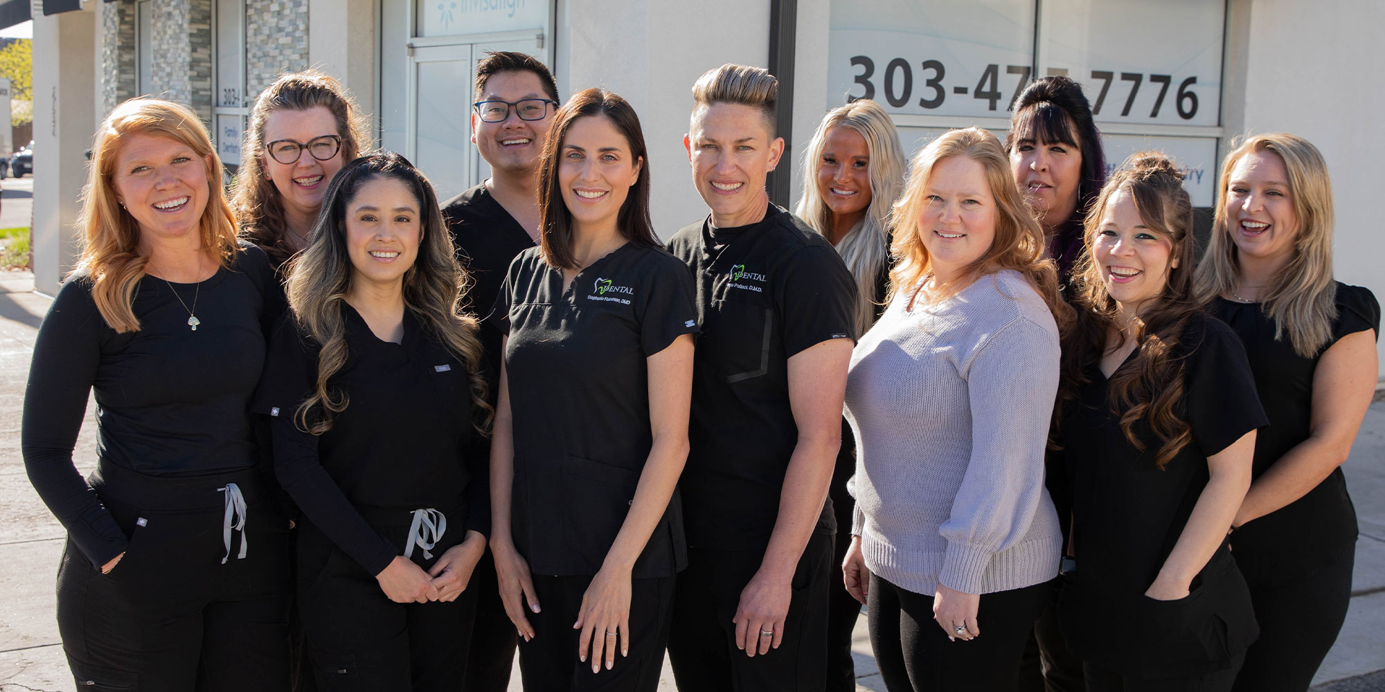 Dentist and their team standing together smiling